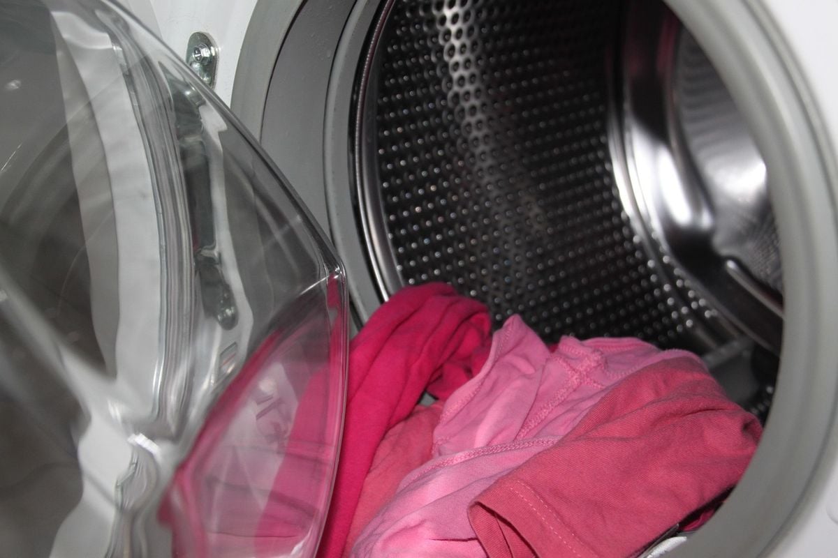 Tambor de máquina de lavar roupa aberto com roupas coloridas dentro