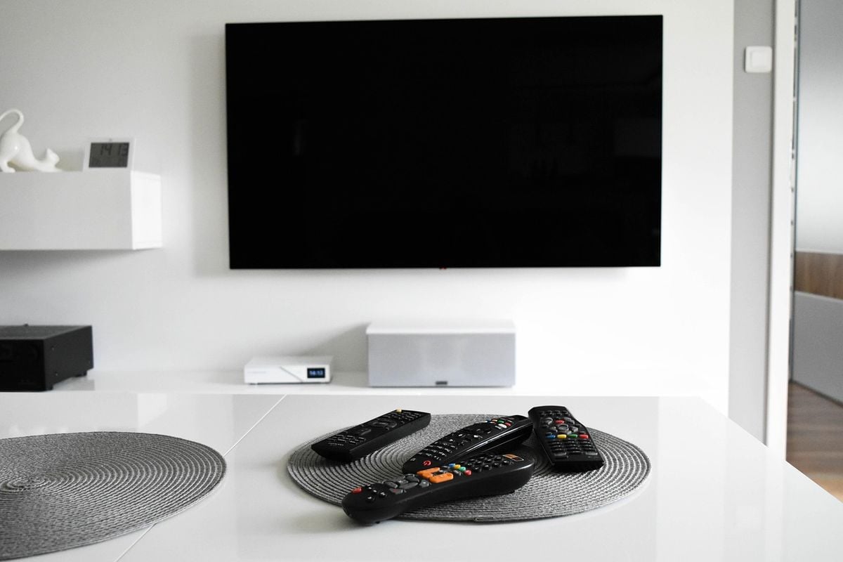 Sala moderna com TV digital instalada na parede e controles sobre a mesa