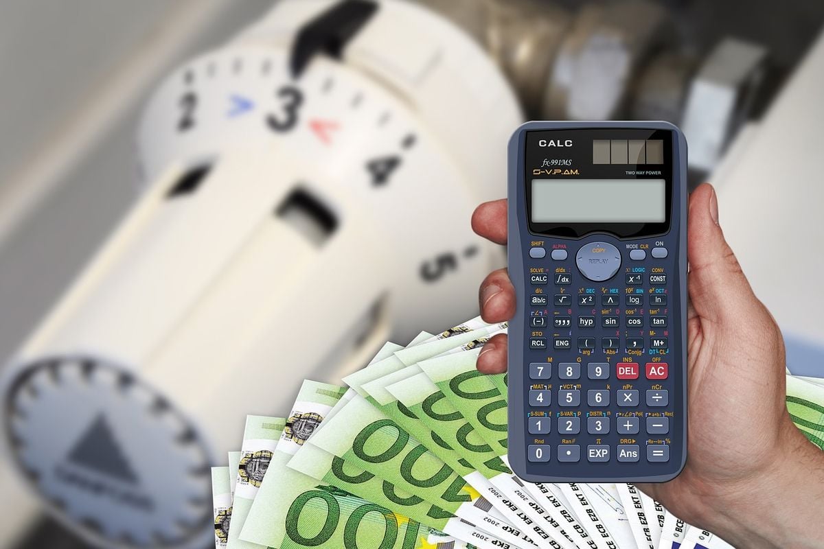 Calculadora na mão diante de medidor de energia e cédulas de dinheiro, representando o preço do ar-condicionado inverter