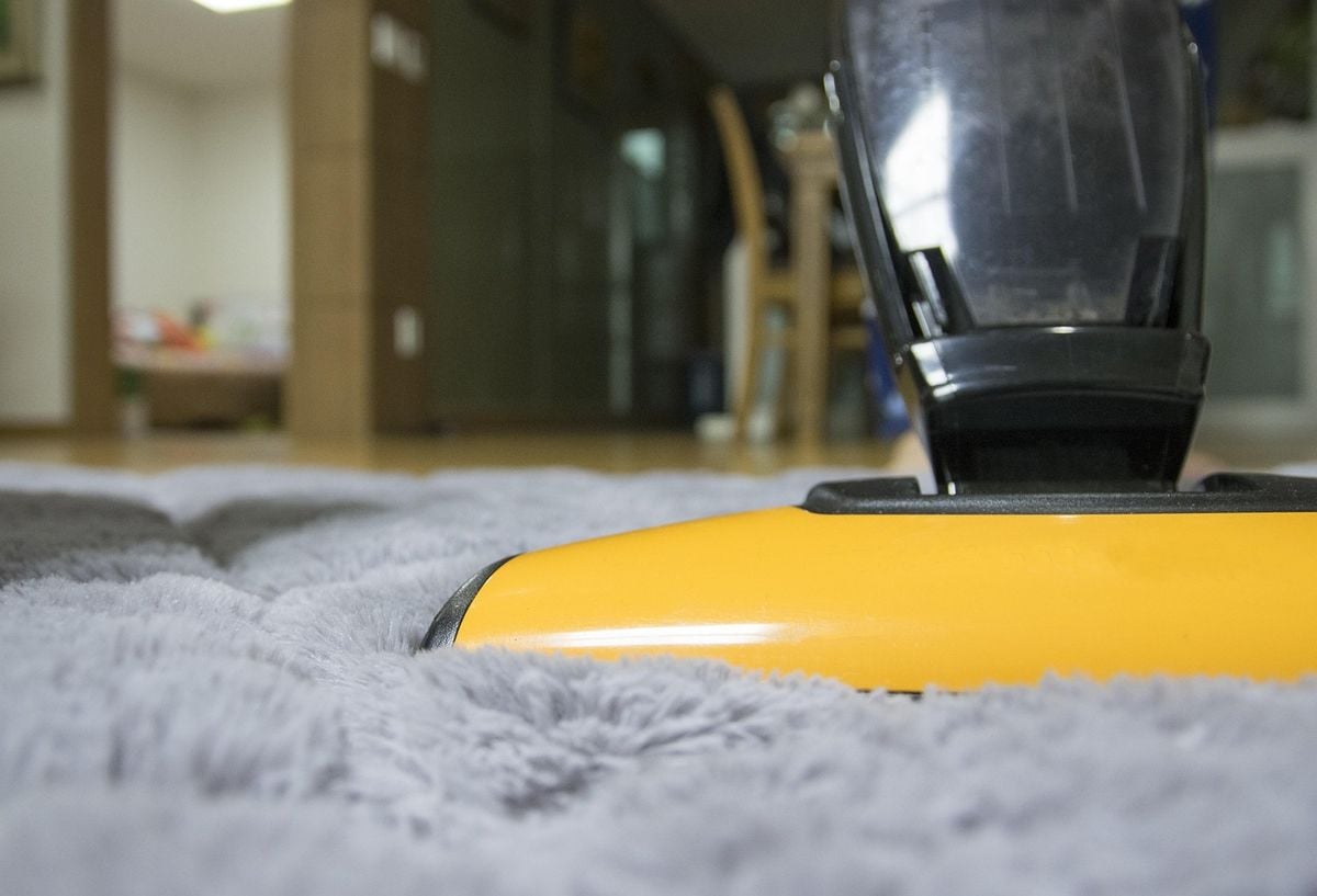 Aspirador portátil em uso sobre tapete felpudo cinza Aspirador portátil amarelo e preto sobre tapete felpudo