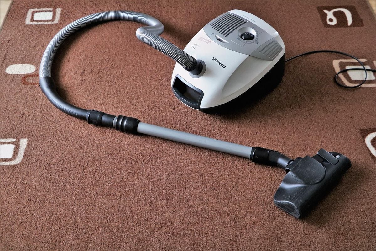 Pessoa usando aspirador de pó em sala de casa