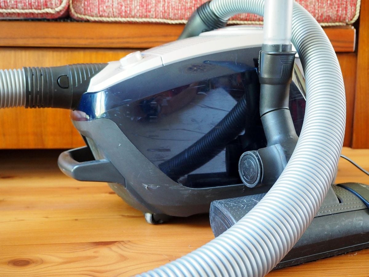 Aspirador de pó em uso no piso de madeira da sala
