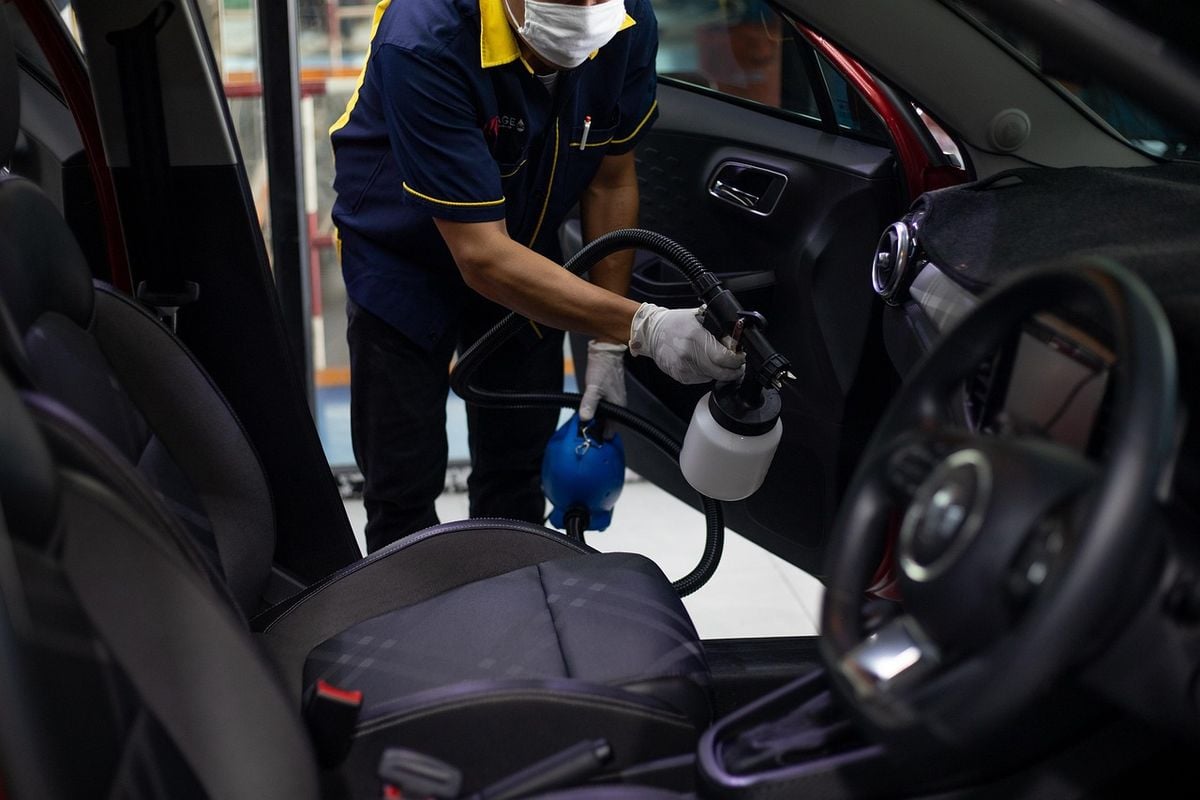 Pessoa limpando o interior do carro com equipamento de limpeza