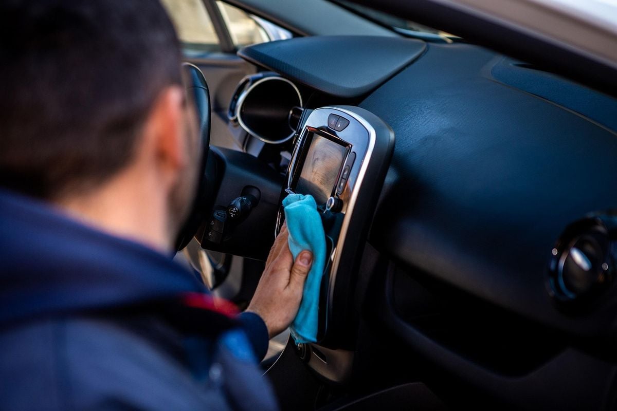 Pessoa limpando o painel e o interior de um carro