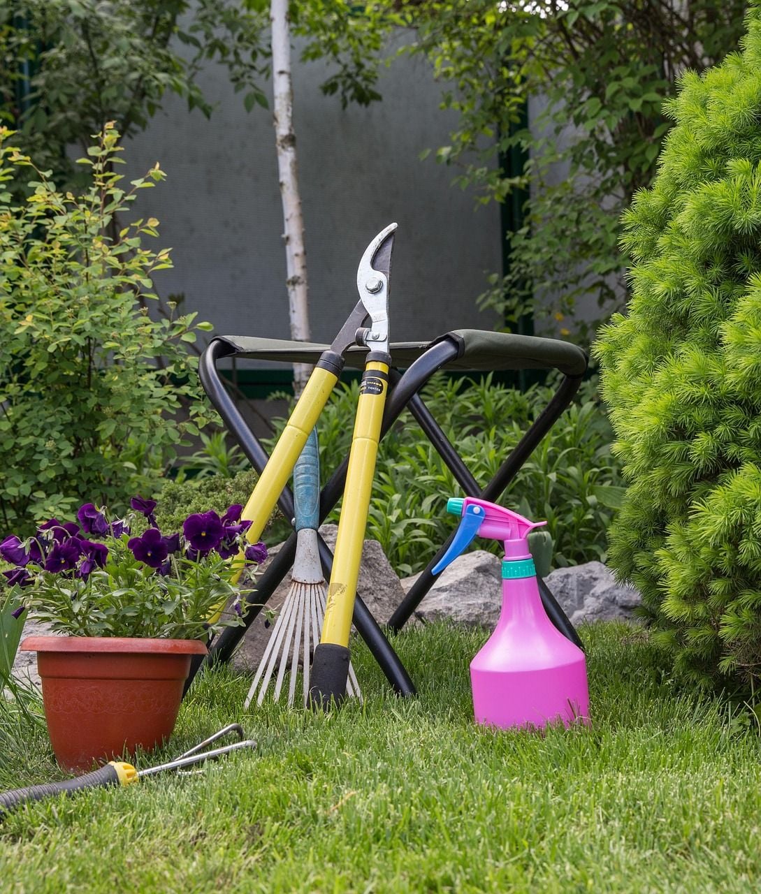 Jardim com ferramentas de limpeza, rastelo e vasos em gramado verde